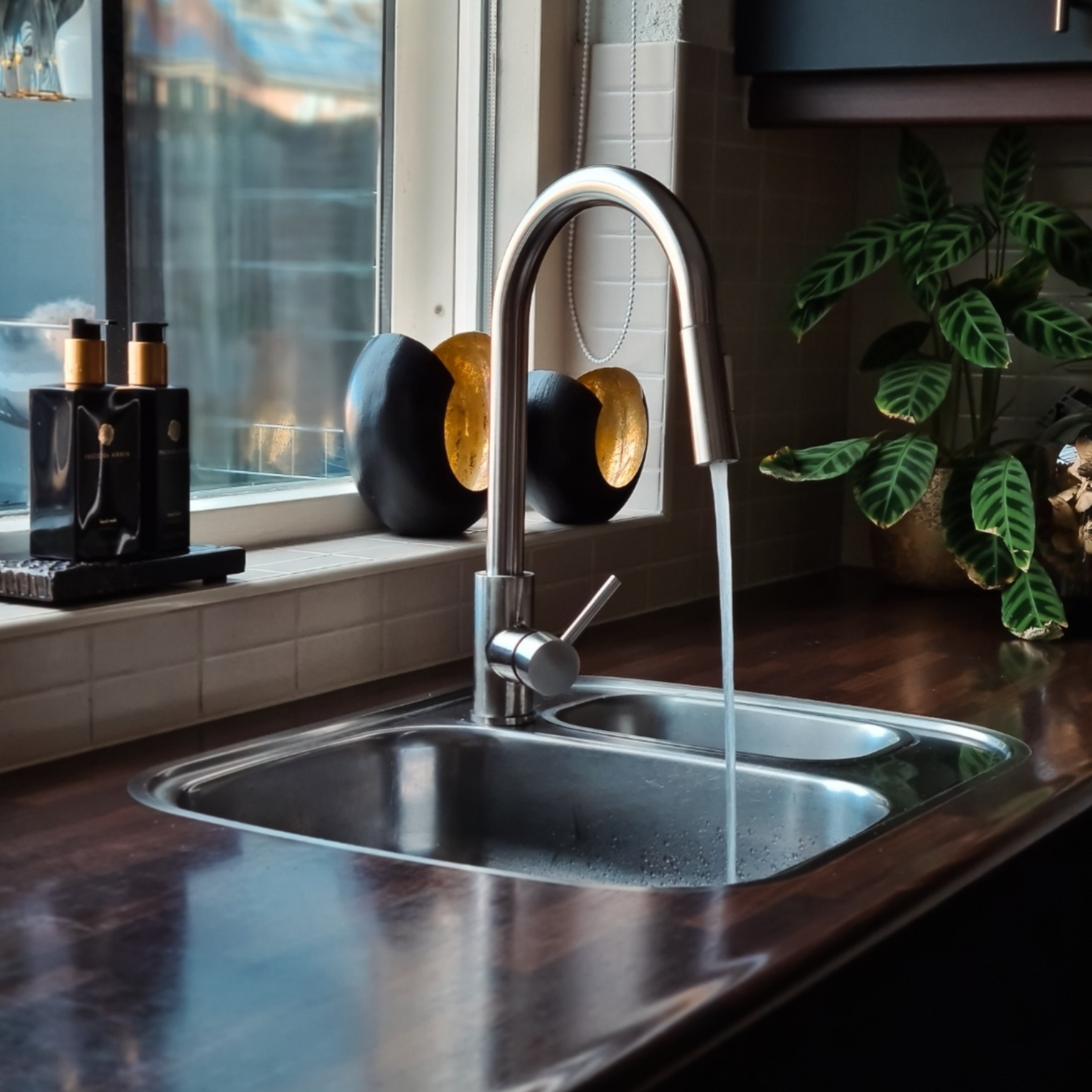 De zilveren keukenkraan in gebruik bij een klant thuis.